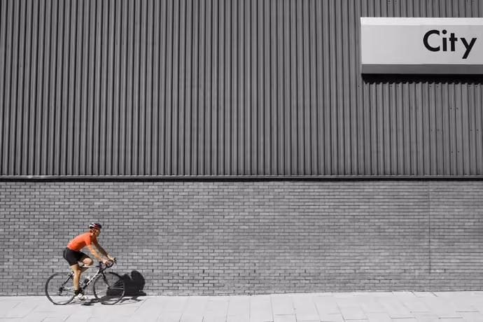 Man cycling past building with 'City' written on side
