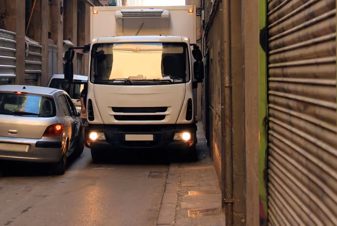 lorry mounts pavement as it negotiates a narrow city street