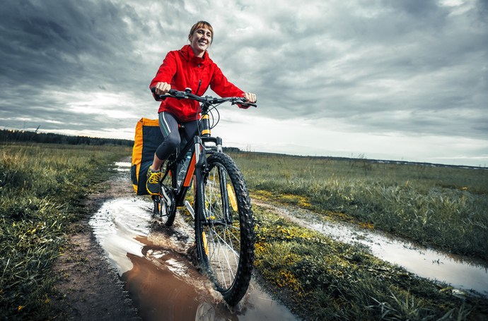 woman riding bicycle down muddy trail in winter