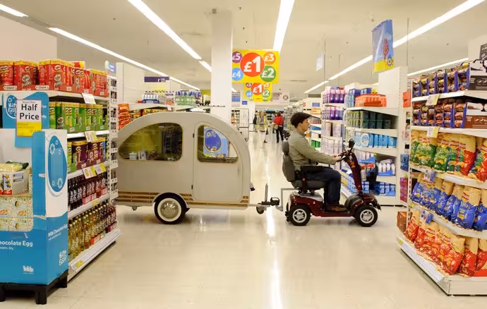 mobility scooter towing small caravan trailer in UK supermarket