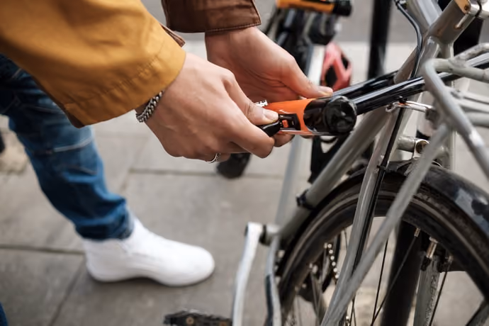 someone using a Kryptonite D-lock to secure a bicycle to a Sheffield stand