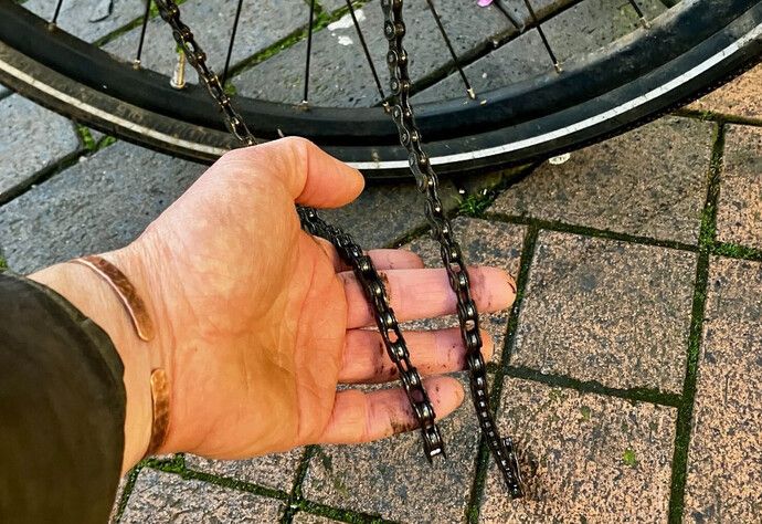 man's hand holding snapped bicycle chain
