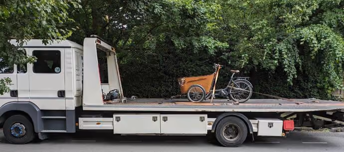 cargo bike strapped to the back of a large recovery lorry