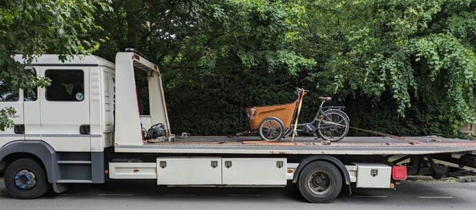cargo bike strapped to the back of a large recovery lorry