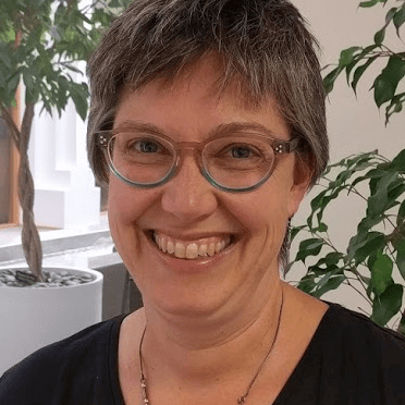 Smiling woman with short hair, wearing glasses.