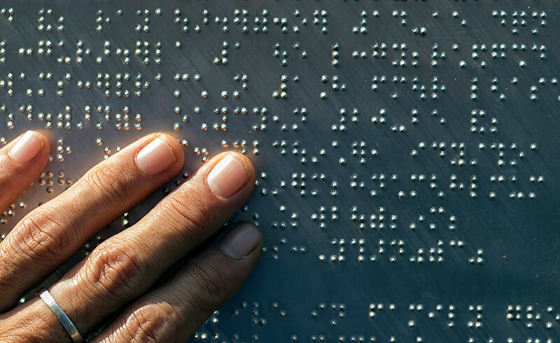 A hand touching braille - Go Beyond Available to Accessible eLearning - eLearning Design - Flare Learning