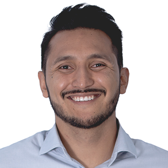 Smiling man with short, dark hair, wearing a pale blue button-up.