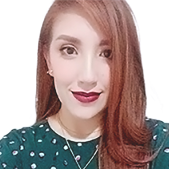 Smiling woman with long, red hair and red lipstick, wearing a green polkadot blouse.