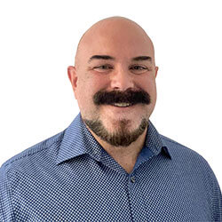 Smiling man with a black mustache and a blue collared shirt
