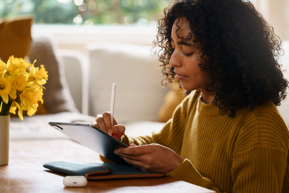 woman writing on a tablet with a pen - Using AI To Write Essays