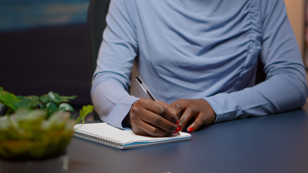 woman writing on a book - Writing Prompts for Students