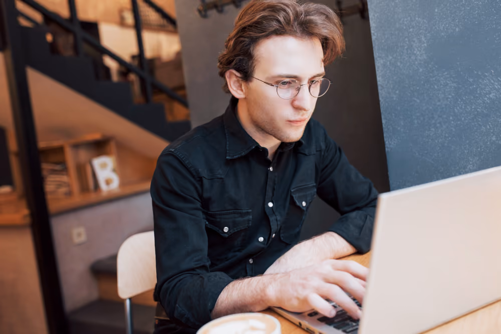 man in a black shirt using a laptop - Why Is My Essay Detected as AI