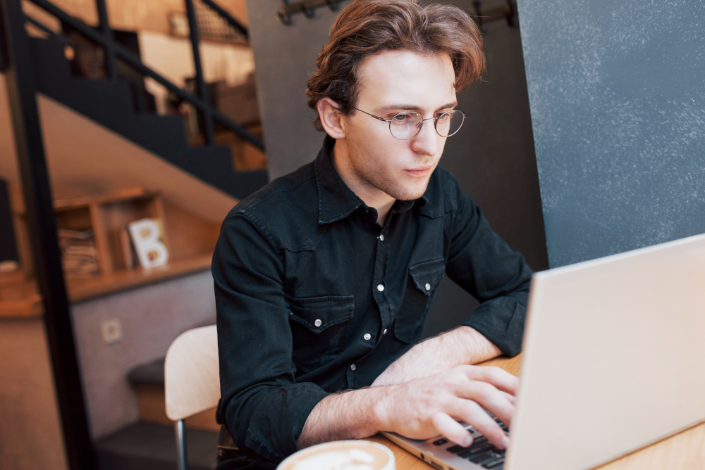 man in a black shirt using a laptop - Why Is My Essay Detected as AI