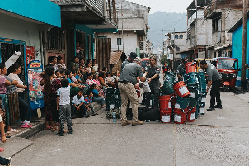 A group of people distributing water filter kits in the street