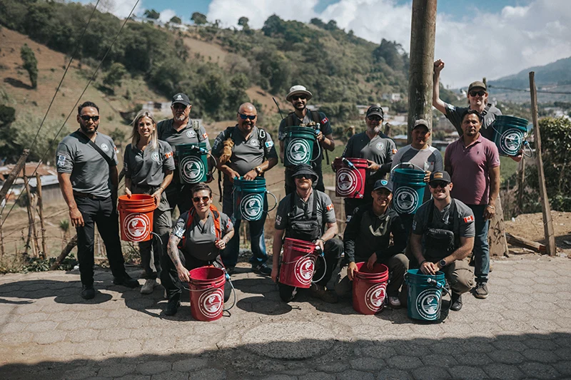 Relief team members posing outside with bucket water filters in hand