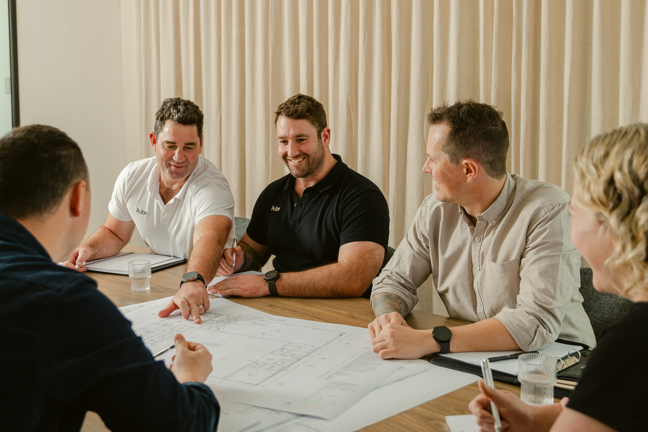 Build and design team sitting around plans discussing and collaborating work together. Relaxed and real photo of teamwork by Dave at Palms photography