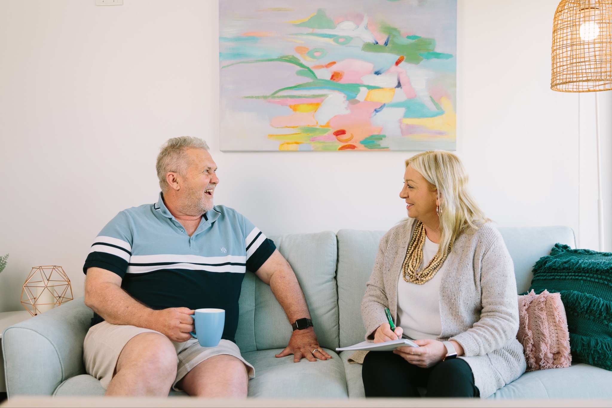 Support worker and participant engage in relaxed conversation on the couch - NDIS branding photography with real people by Palms Photography South Australia