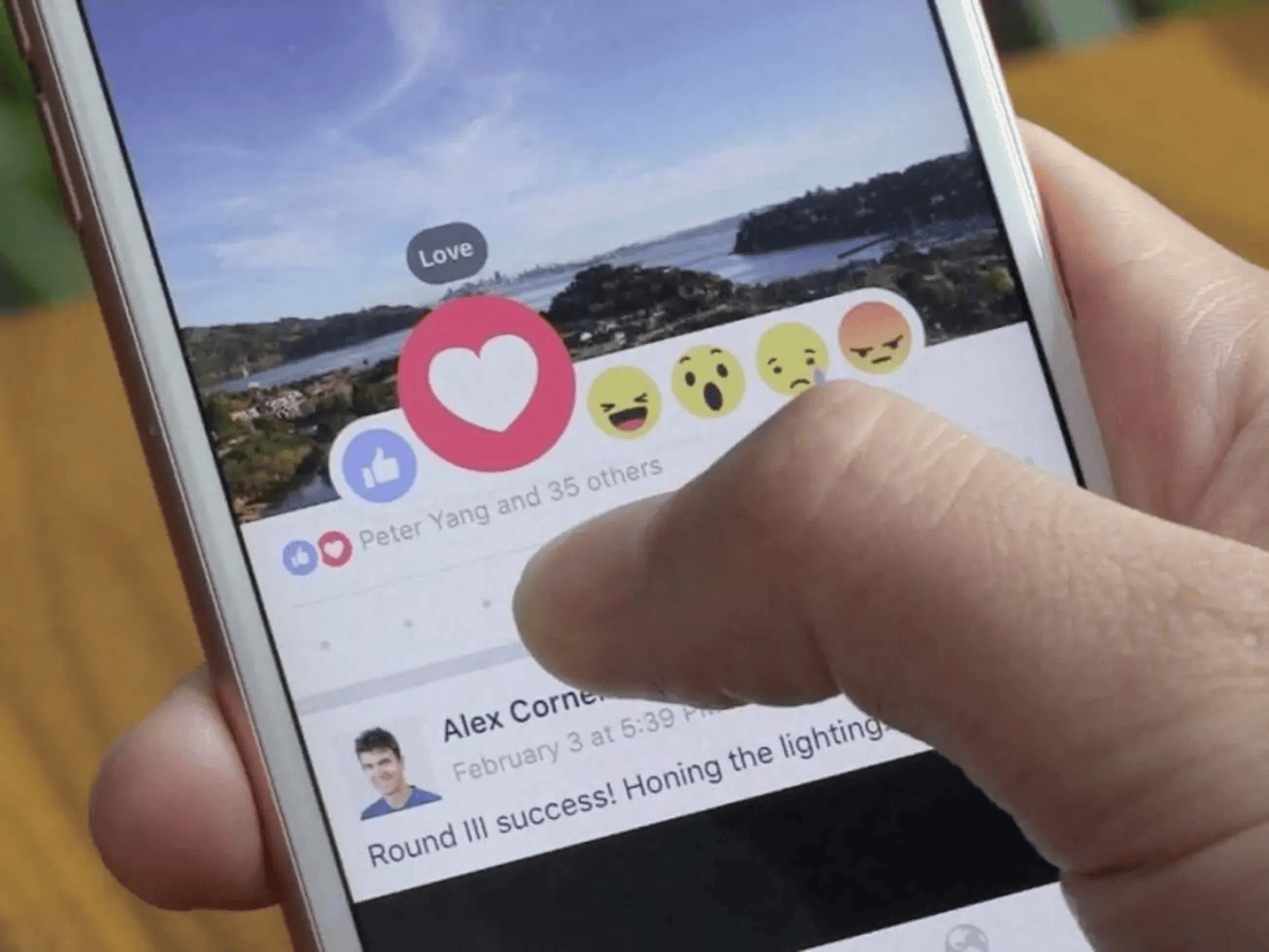 Microinteractions UI: Facebook post with reaction options. User's finger hovers over emoji reactions, showcasing interactive feedback on mobile.