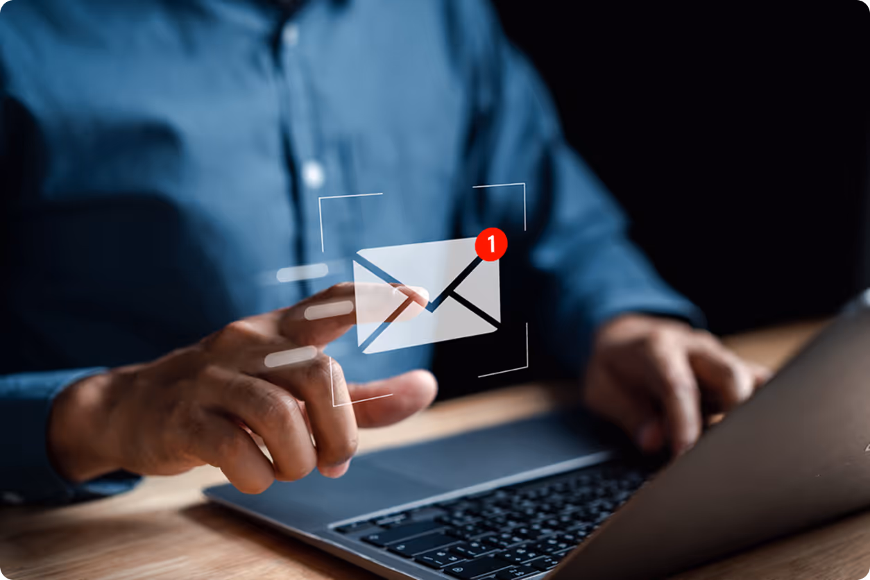 Image of a person working at a laptop with a floating email icon