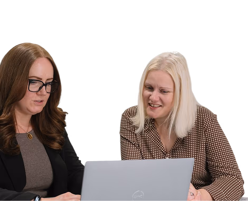 Two women working together looking at a laptop screen, one with glasses and the other smiling.