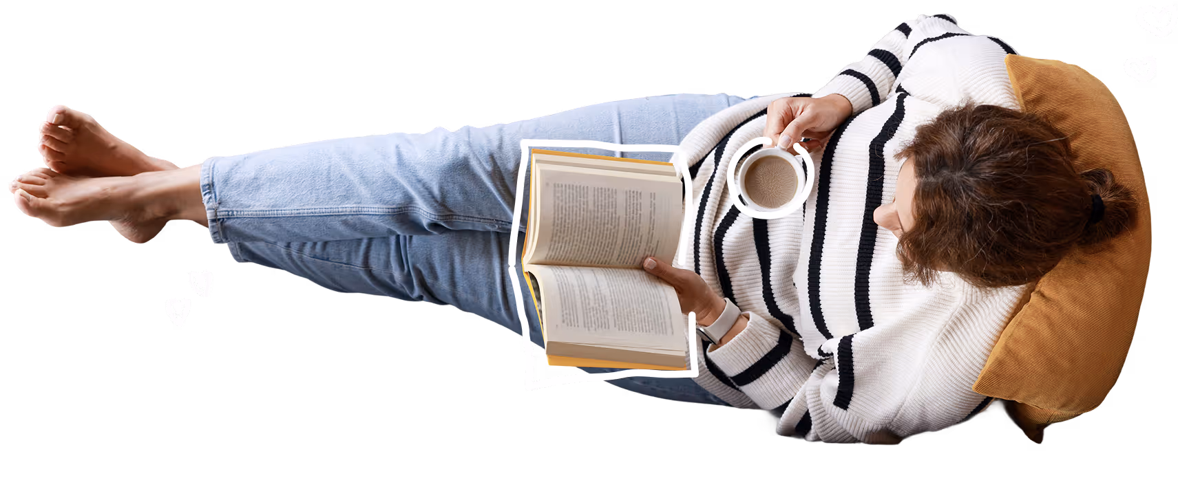 Person lying on a pillow reading a book while holding a cup of coffee.