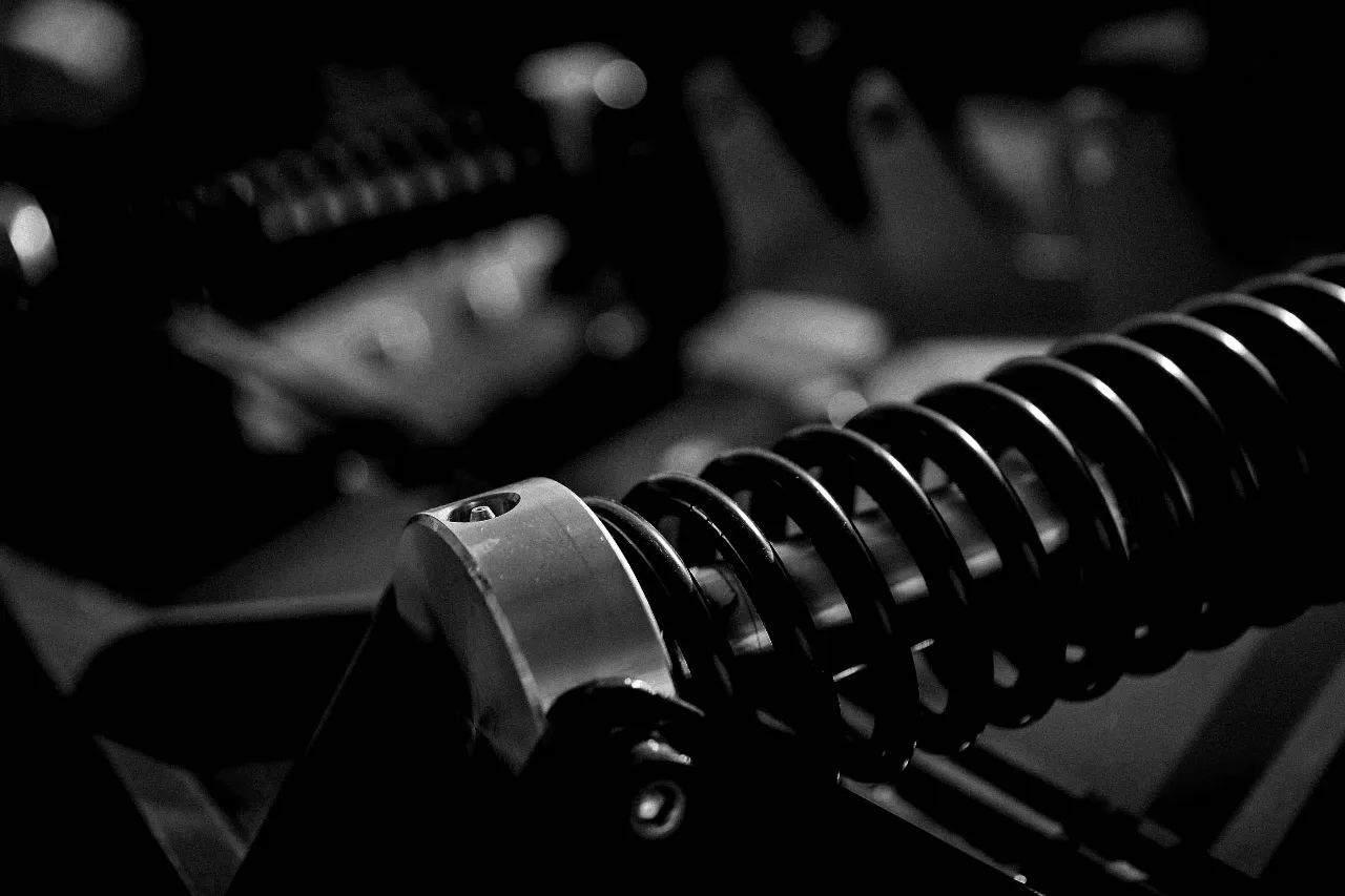 Close-up of a heavy-duty suspension spring showing coil detail and mounting hardware under low lighting.