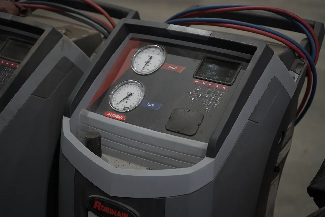 A/C recharge service with Robinair machine showing “HIGH” and “LOW” gauges and model “34788NI” in heavy-duty bay.
