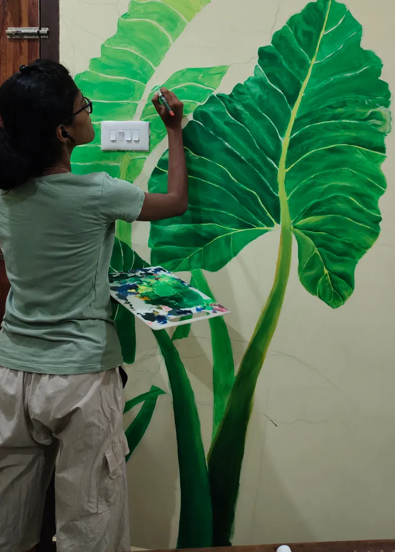 Betsy painting leaves on a wall