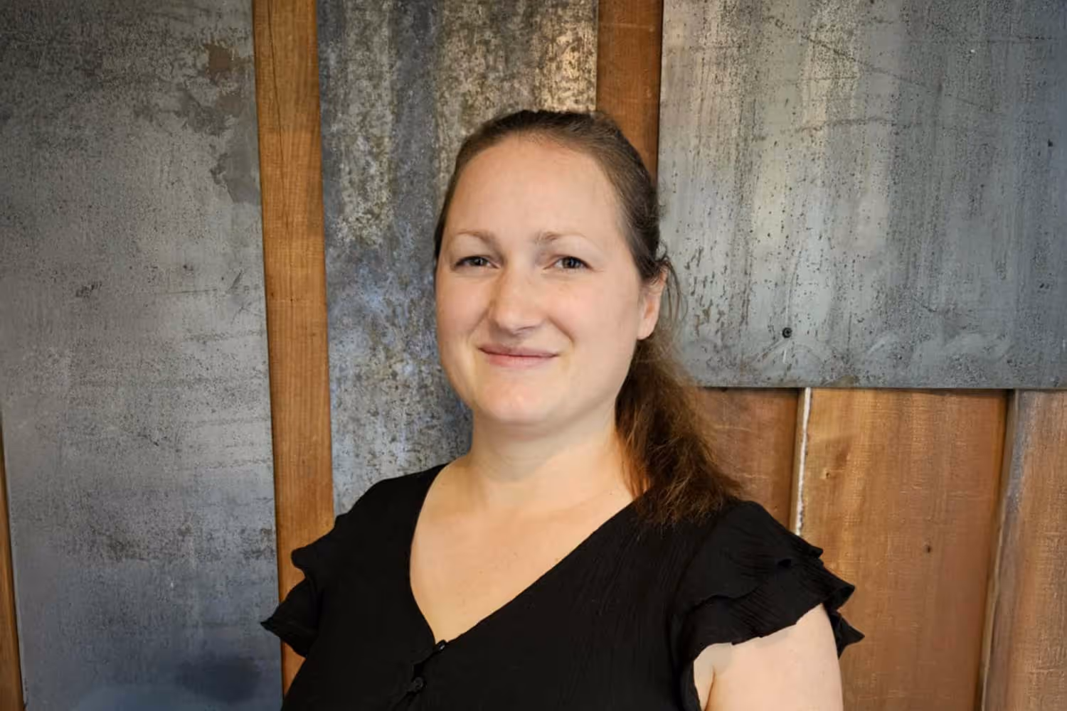 Alex standing in front of a textured wall with wood panels.