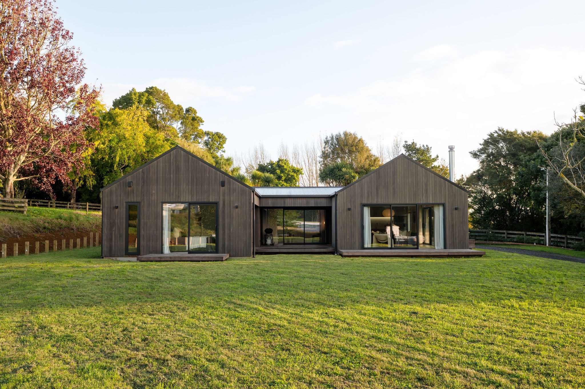Modern single-story house with white and wooden exterior, grey roof, and two-car garage.