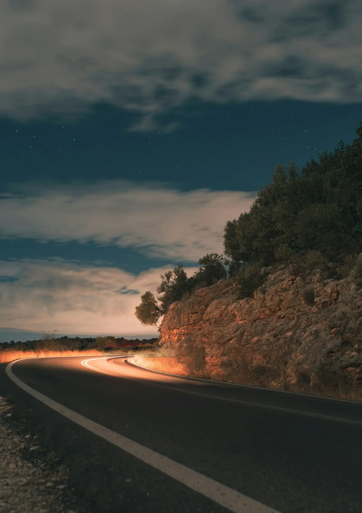 A road below a rock outcrop at dusk