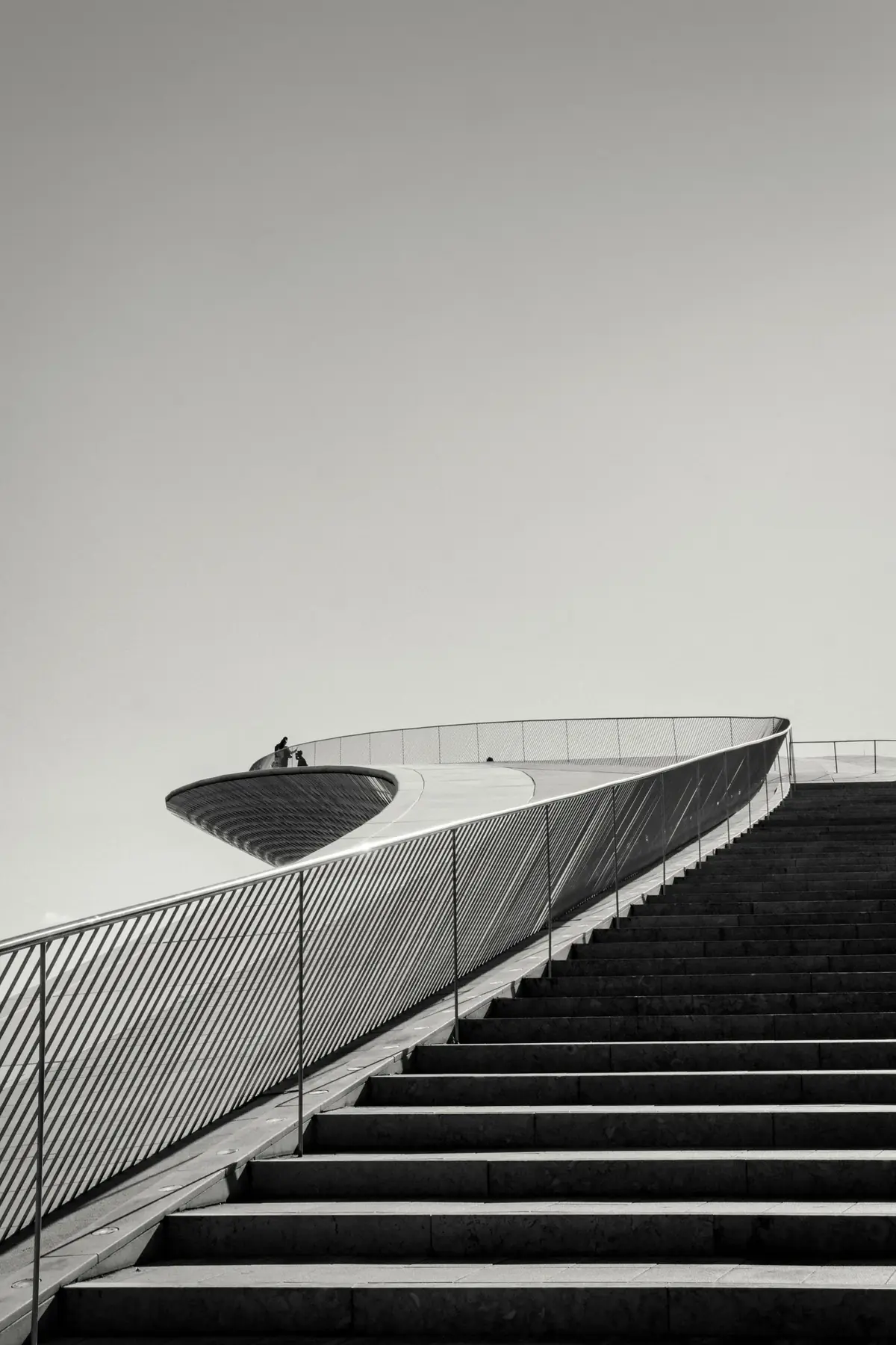 A curved walkway rising above a staircase