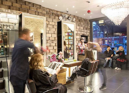 Busy salon floor with stylists working on clients at mirrored stations