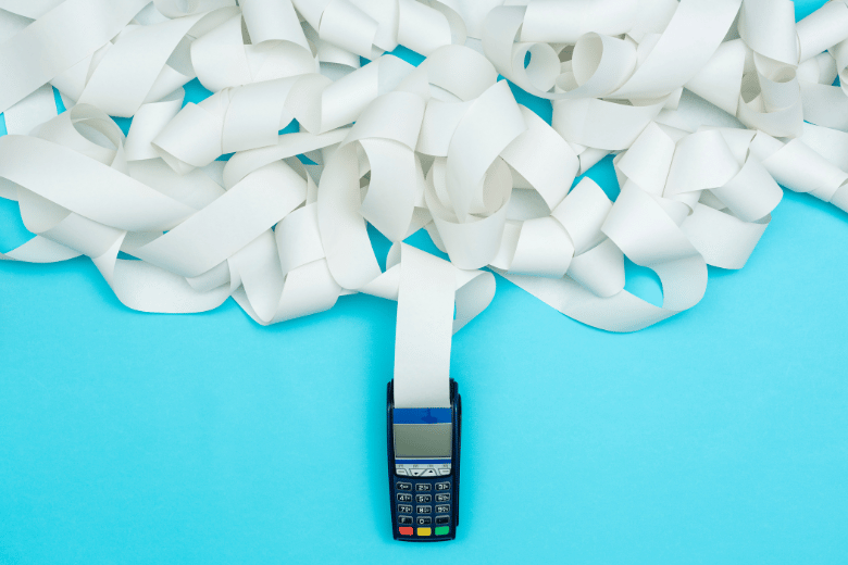 Card payment terminal buried under a pile of paper receipt rolls
