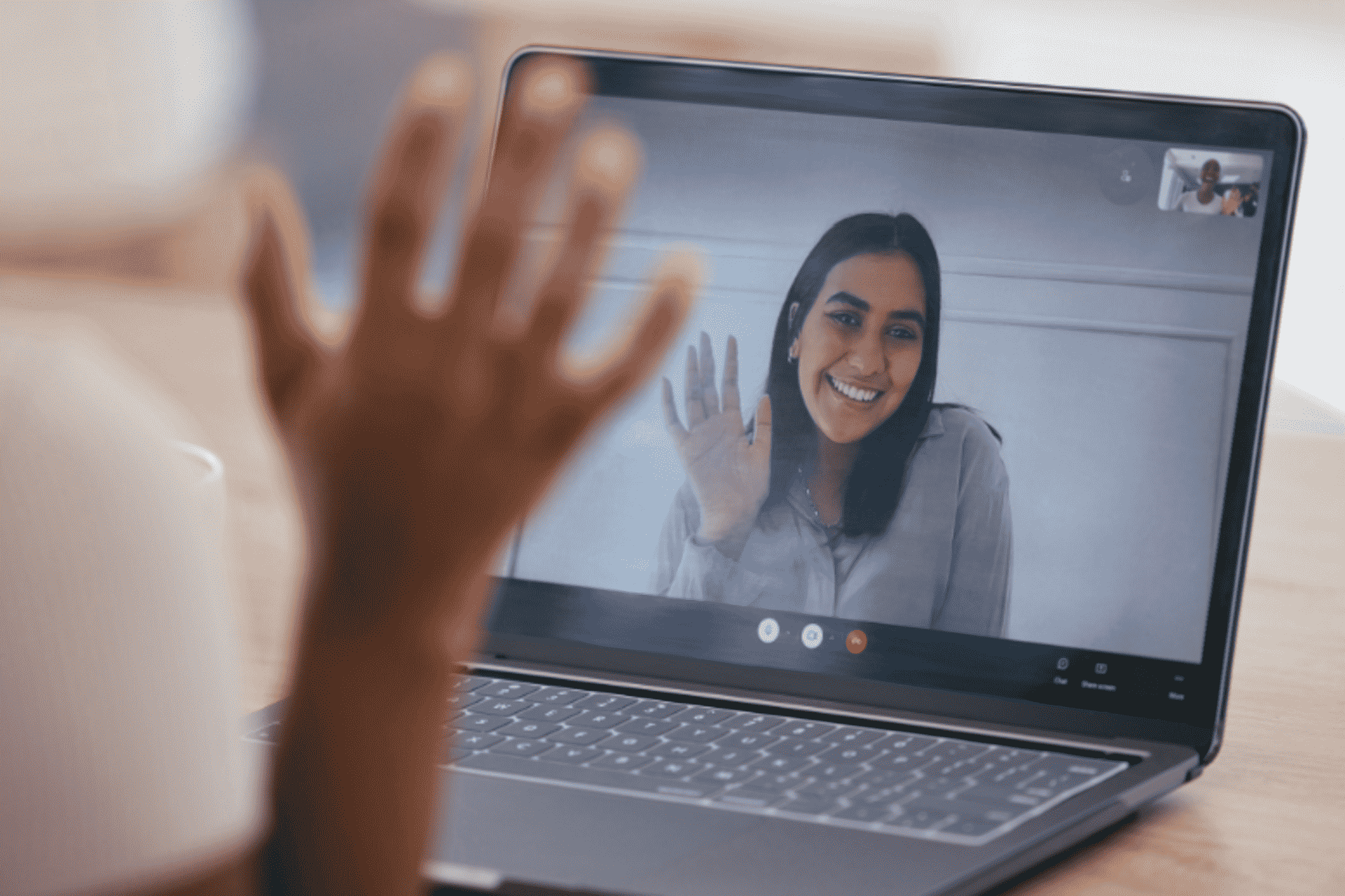 Woman waving on a video call on a laptop screen