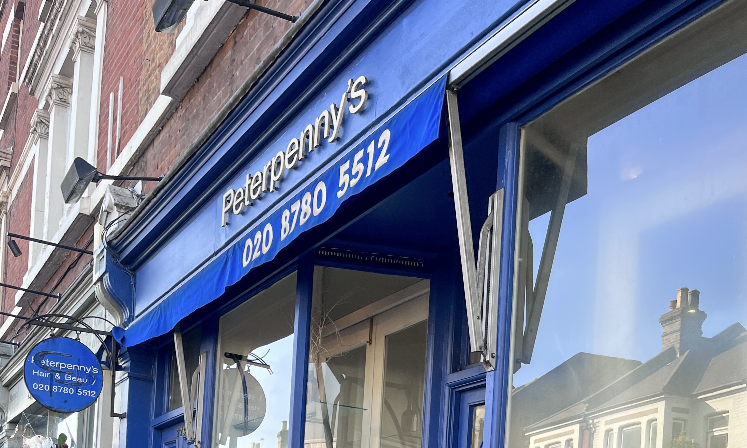 Peterpenny's salon shopfront in London, with a blue awning