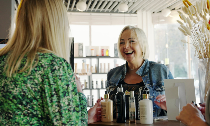 Smiling salon receptionist talking with a client across the front desk