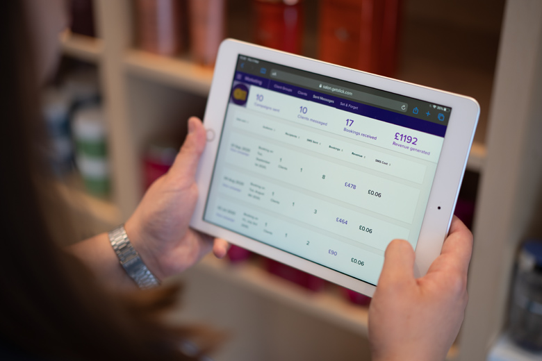 Hands holding a tablet that shows a Slick marketing results dashboard