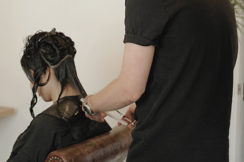 Stylist sectioning a client's dark curly hair with clips