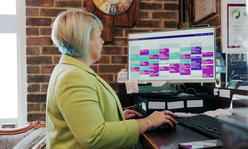 Salon owner at a desktop computer, looking at the Slick appointment calendar