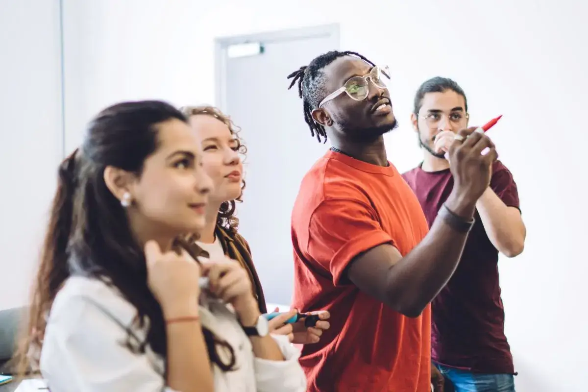 People gathered around looking at something in the distance while holding markers and pencils in their hands.