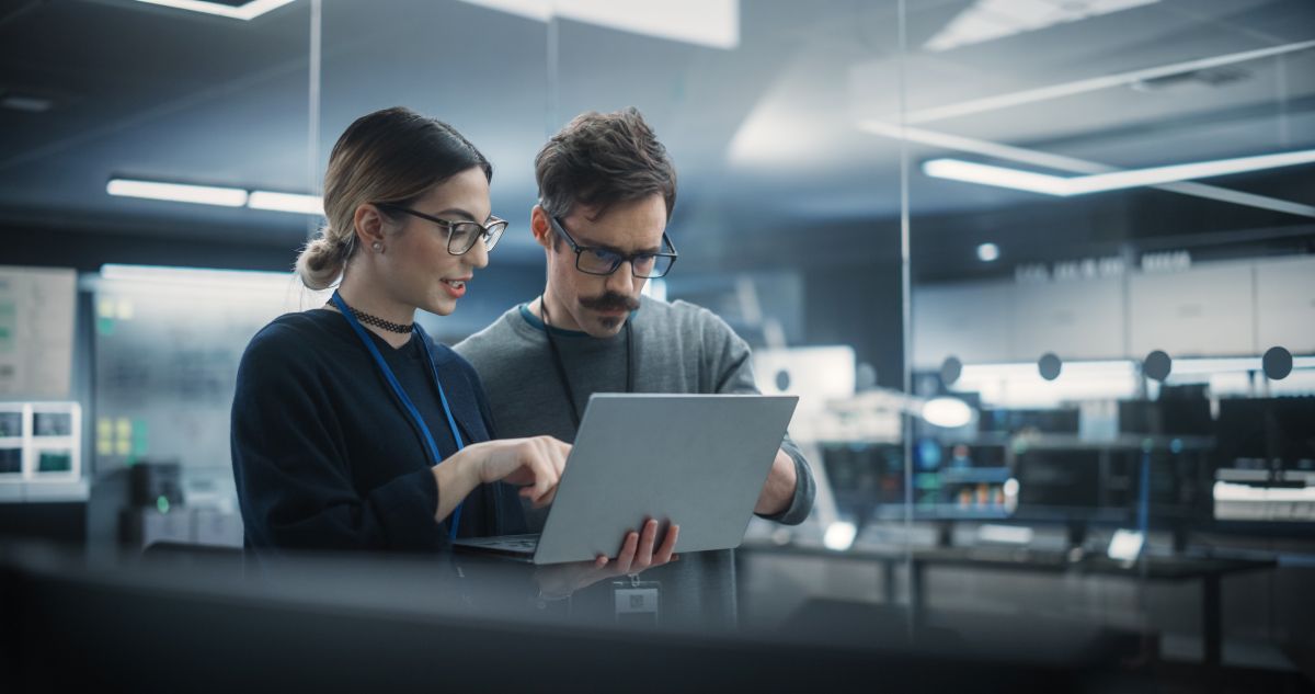 Two people looking at a computer in a manufacturing facility.