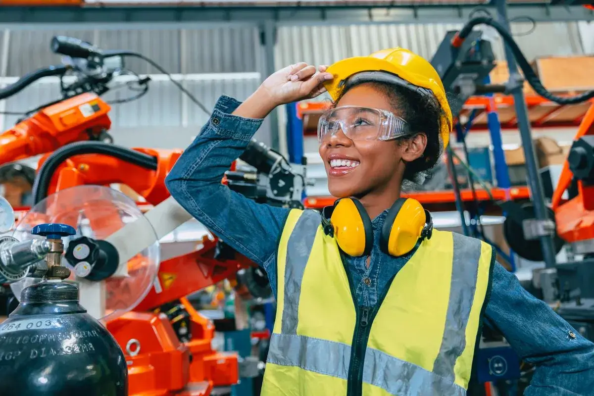 Woman standing in a manufacturing facility with construction gear on.