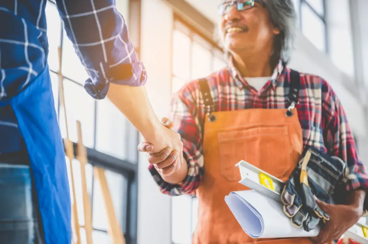 Two people shaking hands in a construction facility.