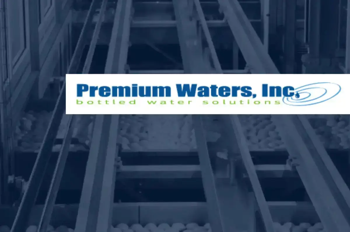 Group of people in gray polos and black pants in a manufacturing facility looking straight at the camera with their arms crossed.