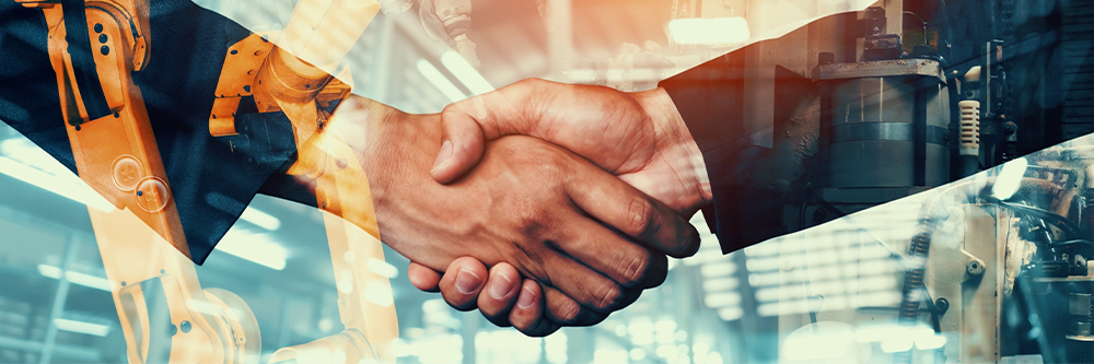 Two hands meet in a handshake in front of machinery