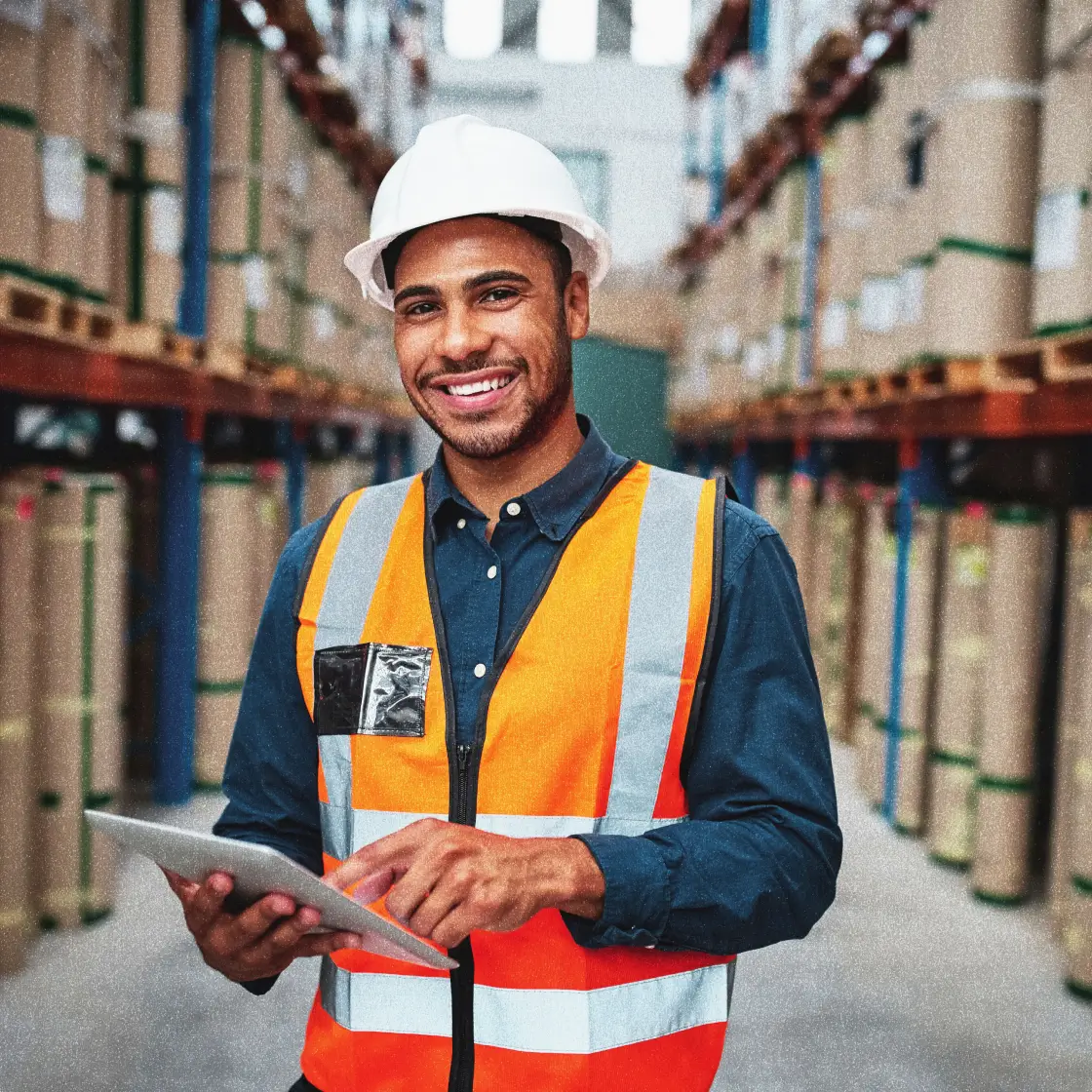 An employee in the shipping department of a growing manufacturing operation smiles at the camera. 