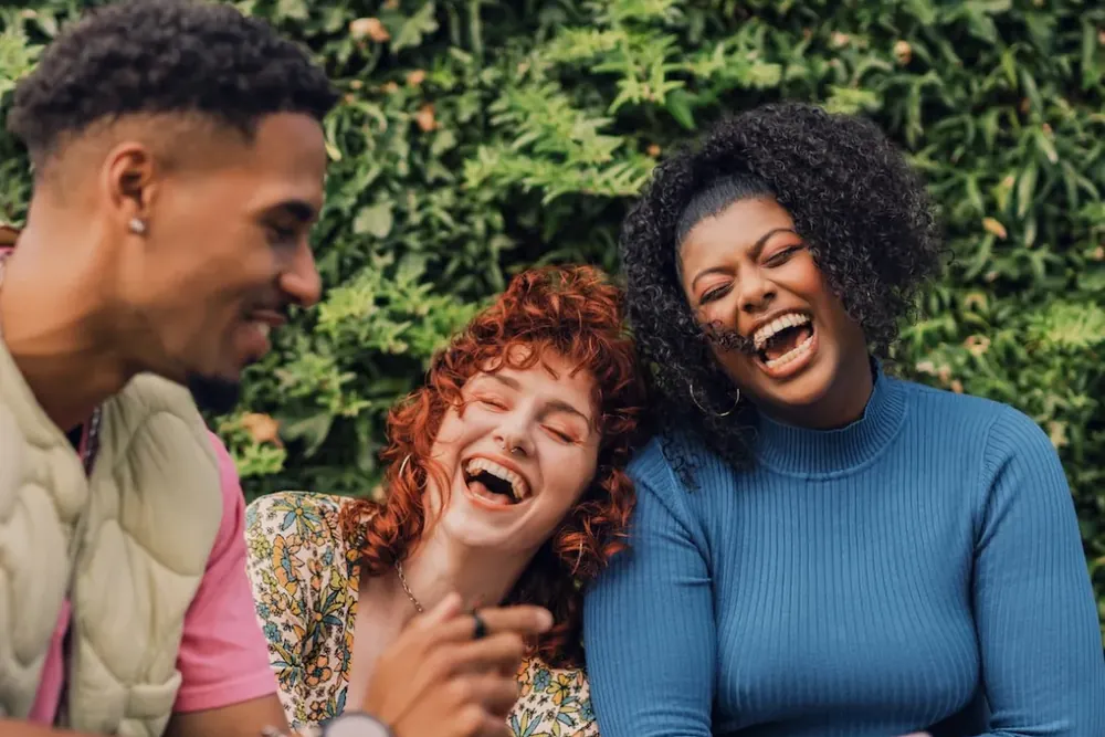 Three friends laughing together outdoors
