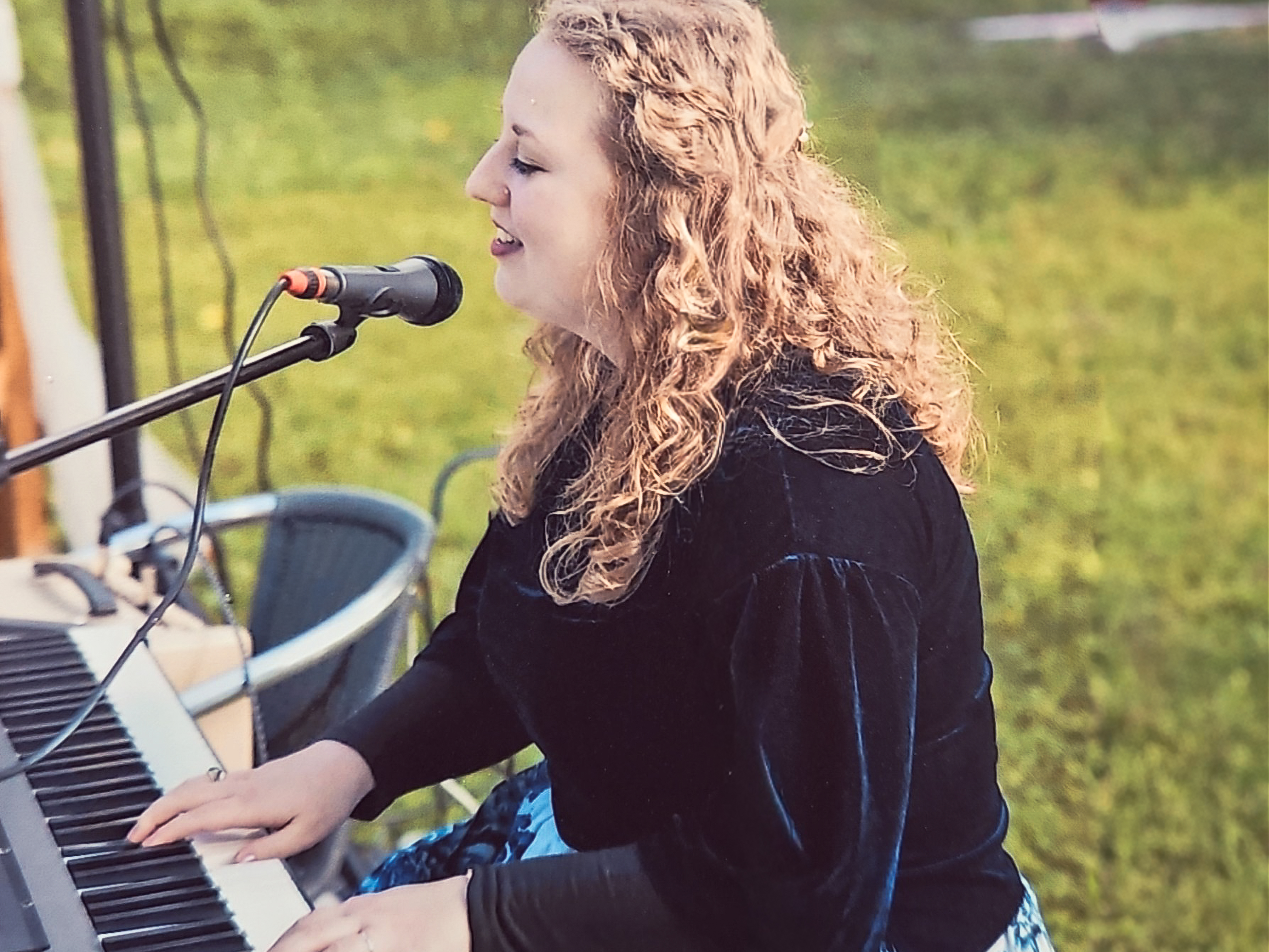 A black polkadotted butterfly sits on a yellow flower. This subject is in front of a deep teal background.