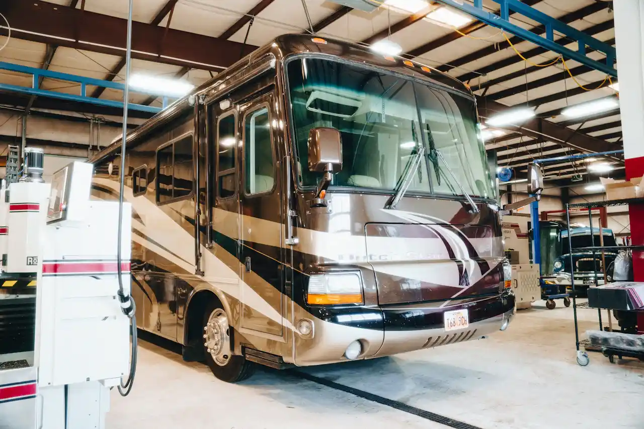Spartan RV service in a heavy-duty repair shop with the motorhome positioned beside diagnostic and repair equipment.